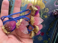 a person holding a pink and gold acorn necklace