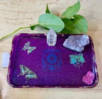 a purple tray with crystals and butterflies on it
