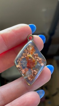 a person holding a small square glass pendant