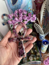 a person is holding a purple flower with a cross on it