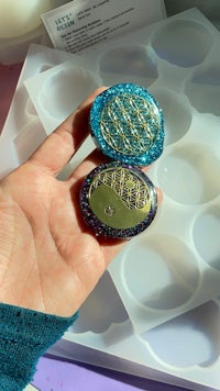 a person is holding a blue and gold brooch