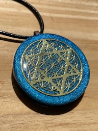 a blue and gold star of life pendant on a wooden table