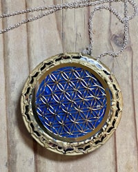 a blue flower of life necklace on a wooden table