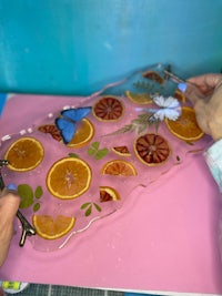 a person is making a glass tray with oranges and butterflies on it