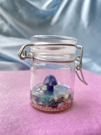 a small glass jar filled with sand and seashells