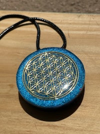 a blue flower of life pendant on a wooden table