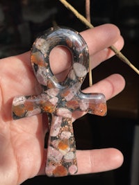 a person holding an ankh pendant in their hand