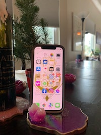 an iphone xs on a table next to a bottle of wine