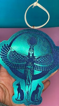 a person holding an ornament with an egyptian design on it