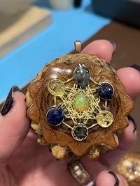 a person holding a piece of wood with gemstones in it