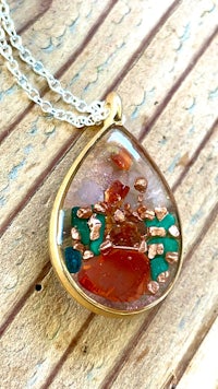 a tear shaped necklace with colorful stones on it