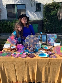 a woman and her daughter standing next to a table full of colorful plates