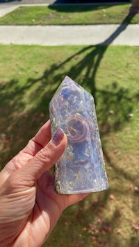 a person holding a small crystal point in their hand