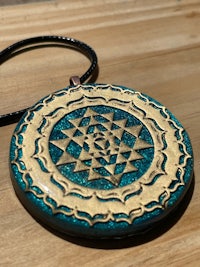 a blue and gold mandala necklace on a wooden table