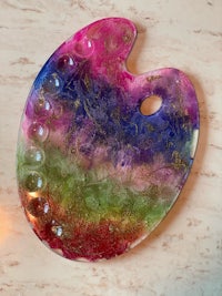 a colorful glass palette on a table next to a candle