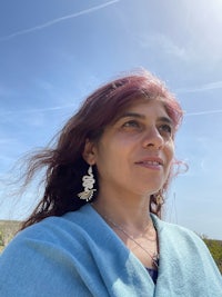 a woman wearing a blue sweater and earrings