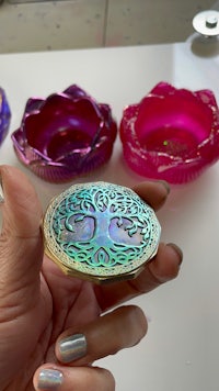 a person is holding a ring with a tree of life design on it