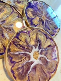 a set of purple and gold coasters on a marble table