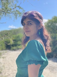 a woman in a green dress standing next to a tree