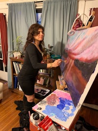 a woman painting on an easel in her living room