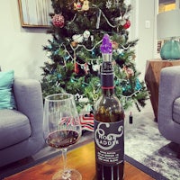 a bottle of wine on a table next to a christmas tree