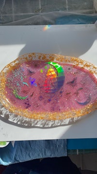 a pink plate on a table next to a white tablecloth